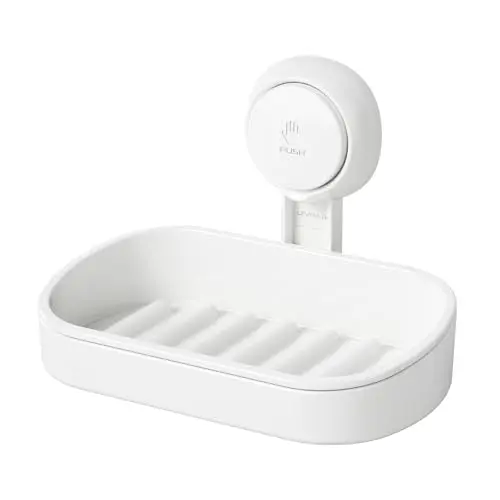 White plastic suction cup soap dish with a push-button activation mechanism, mounted on a shower wall.