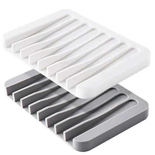 Two soft silicone soap dishes, one white and one grey, with drainage grooves and an inclined design.