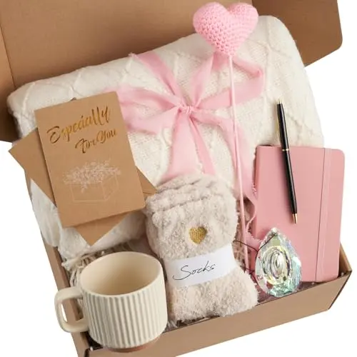 GENERIC pink and white gift box containing a throw blanket, fuzzy socks, a sun catcher, a pink heart, mug, notebook, and pen.